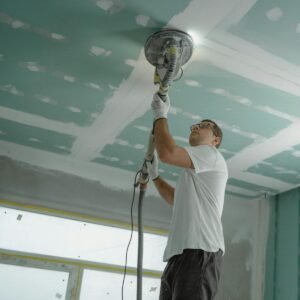 A professional worker sanding the ceiling during a home renovation project. Indoor construction setting.